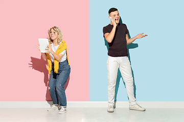 Image showing Young emotional man and woman on pink and blue background