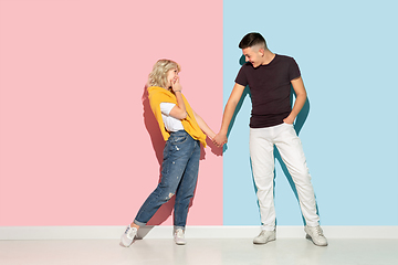 Image showing Young emotional man and woman on pink and blue background