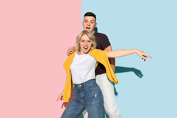 Image showing Young emotional man and woman on pink and blue background