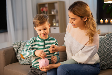 Image showing mother and little son with piggy bank at home