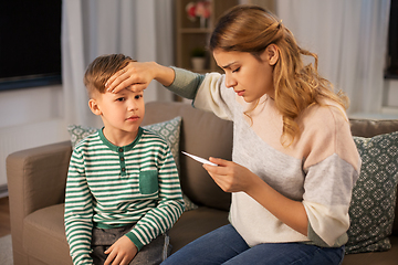 Image showing sad mother with thermometer and ill son at home