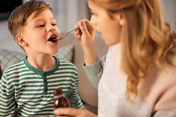 Image showing mother giving medication or cough syrup to ill son