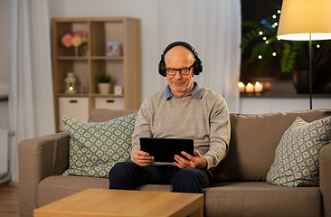 Image showing senior man with tablet pc and headphones at home