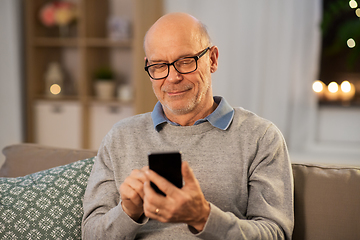 Image showing happy senior man texting on smartphone at home