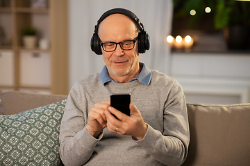 Image showing senior man with smartphone and headphones at home