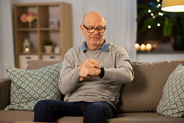 Image showing senior man looking at wristwatch at home