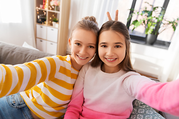 Image showing happy teenage girls taking selfie at home