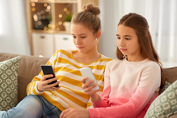 Image showing girls with smartphones sitting on sofa at home