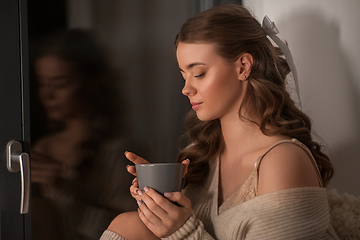 Image showing woman with coffee or tea cup at window at home