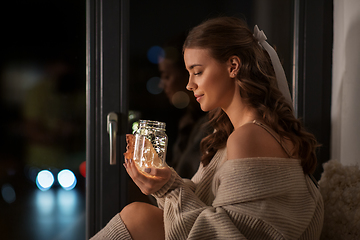 Image showing woman with garland lights in glass mug at home