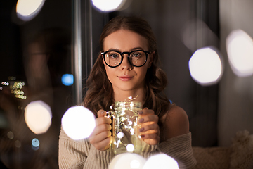 Image showing woman with garland lights in glass mug at home