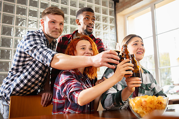 Image showing Group of friends watching sport match together. Emotional fans cheering for favourite team, watching on exciting game. Concept of friendship, leisure activity, emotions