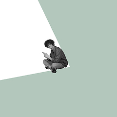 Image showing Modern design, contemporary art collage. Inspiration, idea, trendy urban magazine style. Young man sitting in white angle on pastel green background