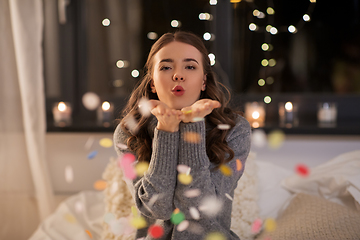 Image showing woman blowing confetti from her hands at home