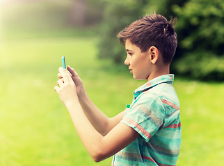 Image showing boy with smartphone playing game in summer park