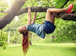 Image showing happy little girl hanging on tree in summer park