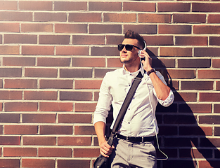 Image showing young man in headphones with bag over brickwall