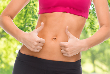 Image showing close up of woman showing tummy and thumbs up