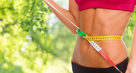 Image showing close up of woman measuring her waist with tape