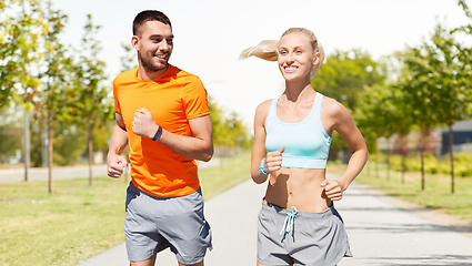 Image showing happy couple with fitness trackers running outdoor