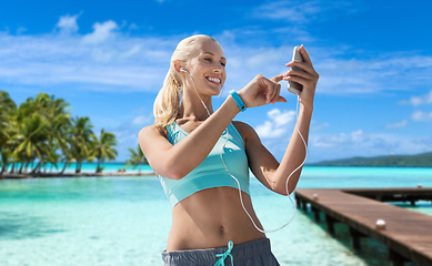 Image showing happy woman with smartphone and earphones on beach