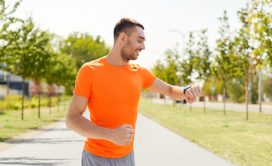 Image showing smiling man with smart watch running outdoors