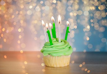 Image showing green cupcake with six burning candles on table