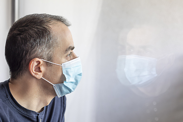 Image showing Young man with medical mask looking out the window