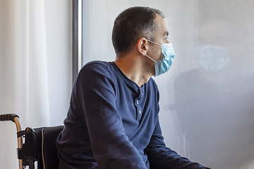 Image showing Young man with medical mask looking out the window