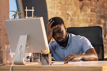 Image showing African businessman, manager working in modern office using devices and gadgets