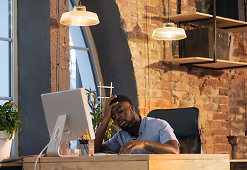 Image showing African businessman, manager working in modern office using devices and gadgets