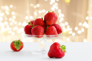 Image showing strawberries on glass stand over white background