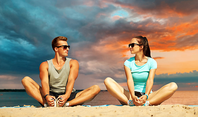 Image showing smiling couple stretching legs on beach