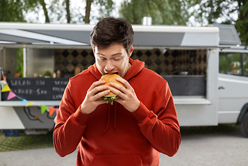 Image showing hungry young man eating hamburger at food truck