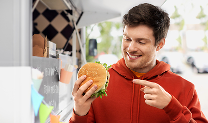 Image showing happy young man showing hamburger at food truck