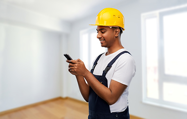 Image showing happy indian or builder in helmet using smartphone