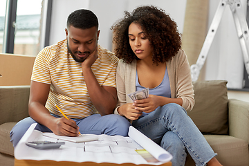 Image showing sad couple with blueprint counting money at home