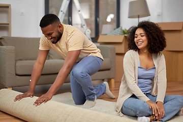 Image showing happy couple with carpet moving to new home