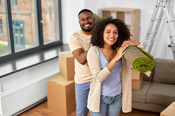 Image showing happy couple with carpet moving to new home