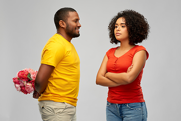 Image showing man hiding bunch of flowers behind back from woman