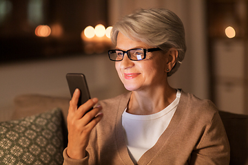 Image showing happy senior woman with smartphone at home
