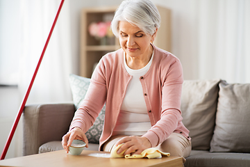 Image showing senior woman cleaning table with soda at home