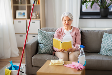 Image showing senior woman reading book after home cleaning