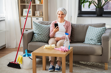 Image showing senior woman using smartphone after cleaning home