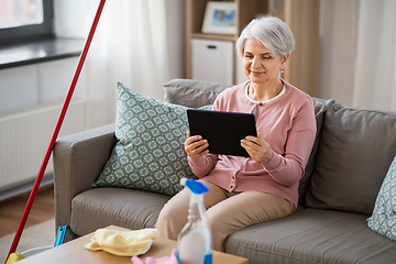 Image showing senior woman using tablet pc after cleaning home