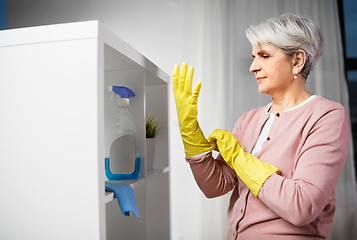 Image showing senior woman putting protective rubber gloves on