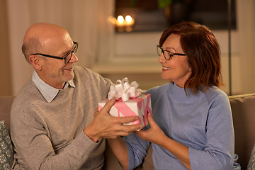 Image showing happy senior couple with gift box at home