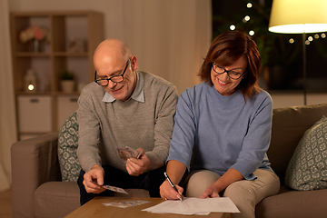 Image showing senior couple with bills counting money at home