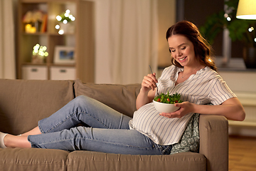 Image showing happy smiling pregnant woman eating salad at home