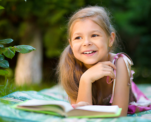 Image showing Little girl is reading a book outdoors